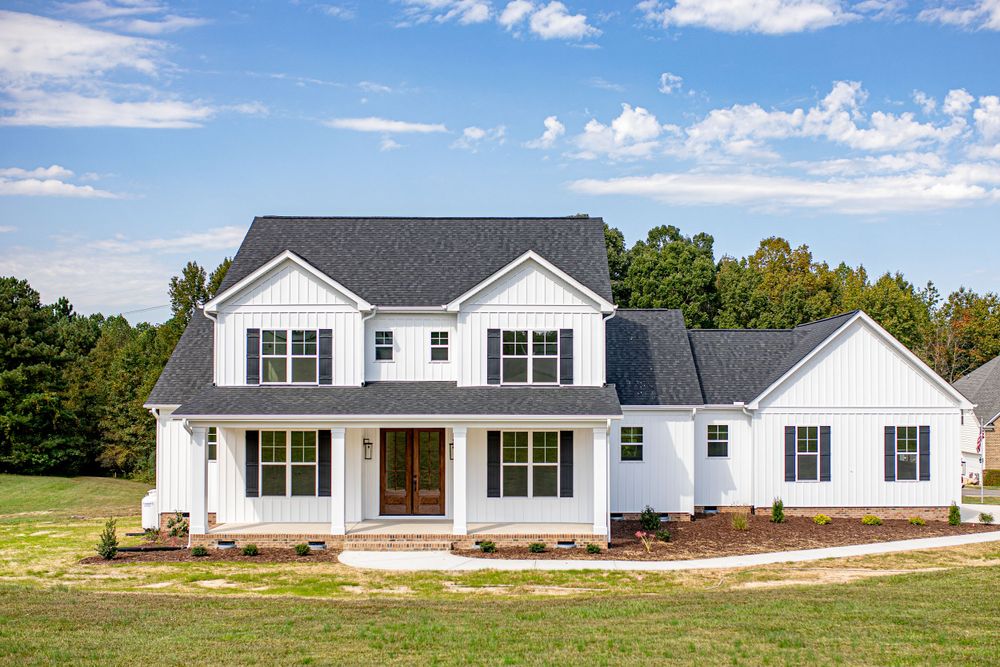 Modern white farmhouse style home exterior with large front porch under blue sky.