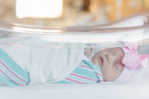 Close up view of sleeping baby wrapped in soft pastel blankets.