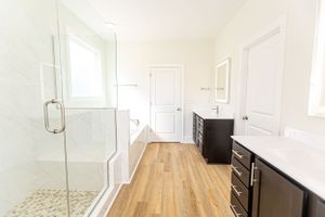 Spacious white interior room with hardwood floors and large windows.