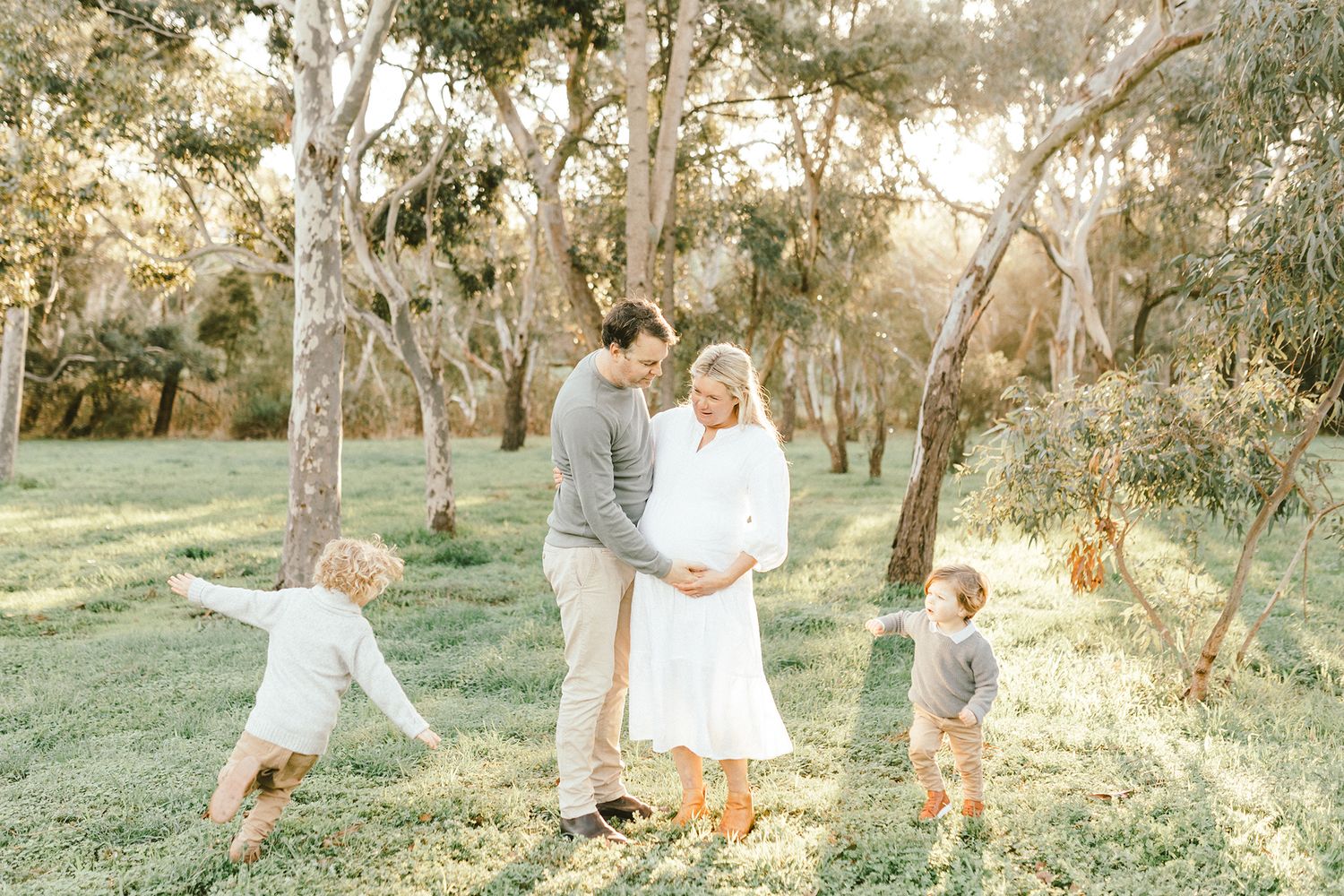A romantic maternity photo session in a sun-filled field with eucalyptus trees.