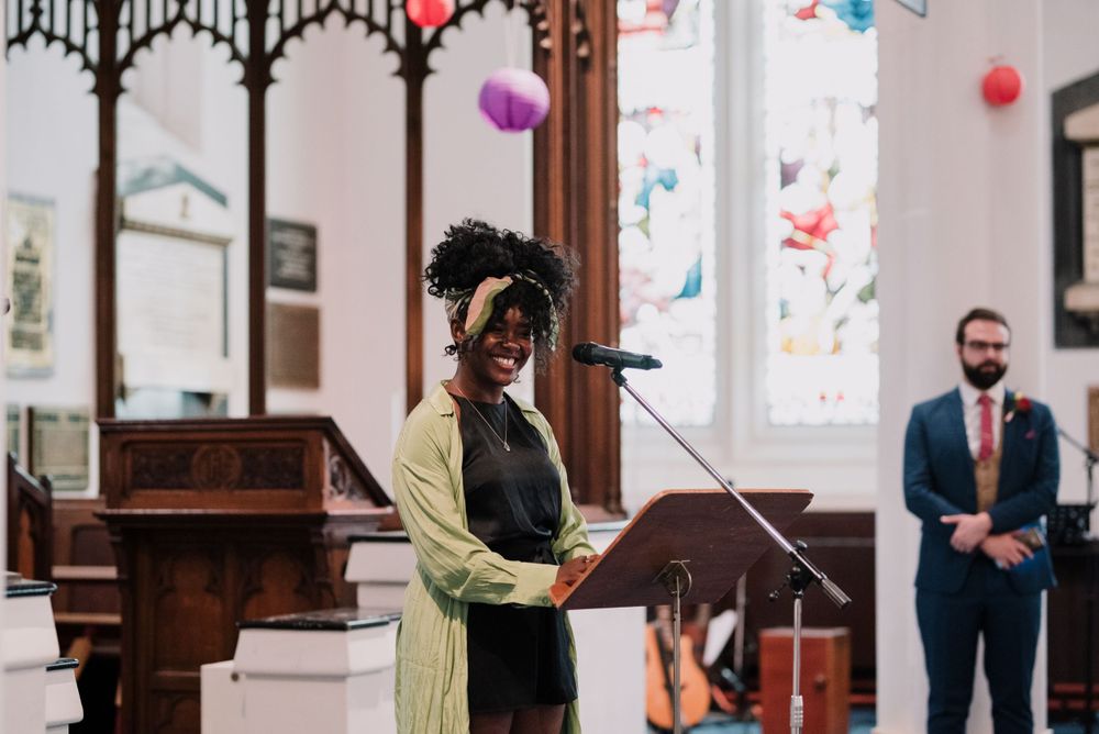A speaker stands at podium in church decorated with colorful paper lanterns.