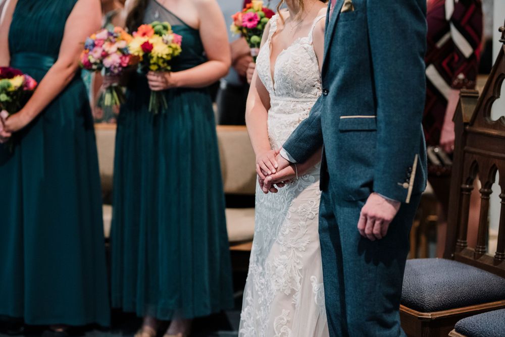 Wedding party members in navy dresses and suits stand during ceremony.