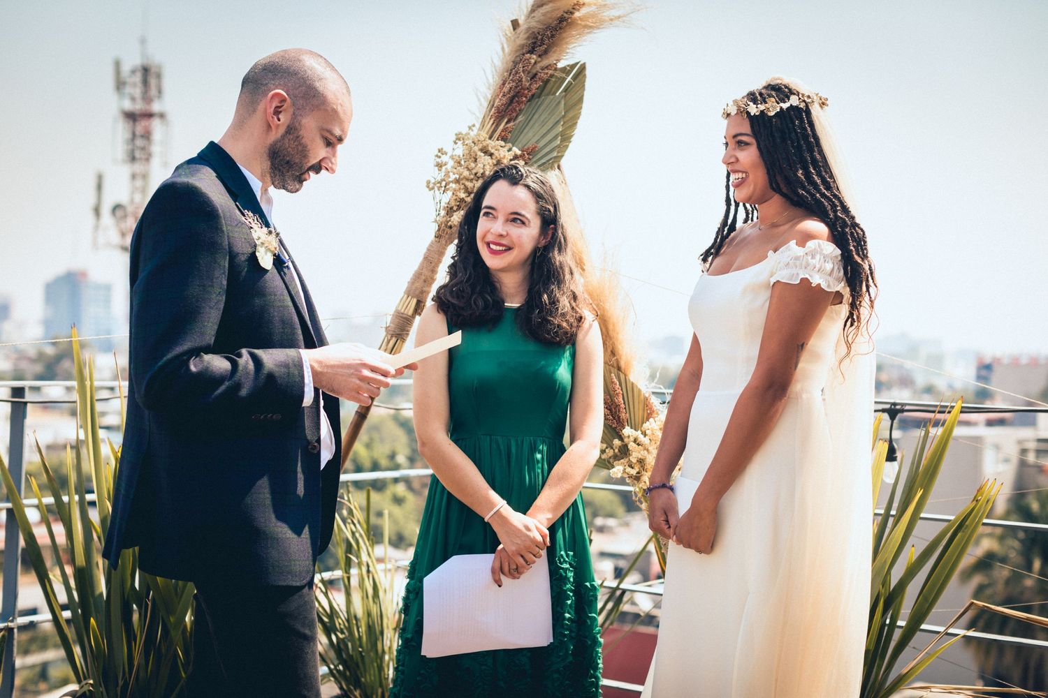 A group celebrating outdoors on a sunny rooftop with drinks and lively conversation.