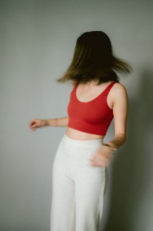 Dynamic motion shot of person in red top and white pants with hair in movement.