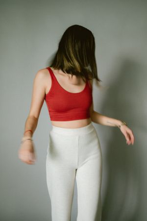 Side view of figure in red crop top and white pants in casual motion pose.