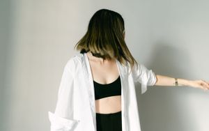 Fashion portrait with white oversized shirt and black crop top in studio setting.