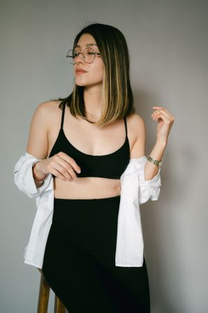 Contemporary fashion portrait in black outfit and white shirt with glasses.