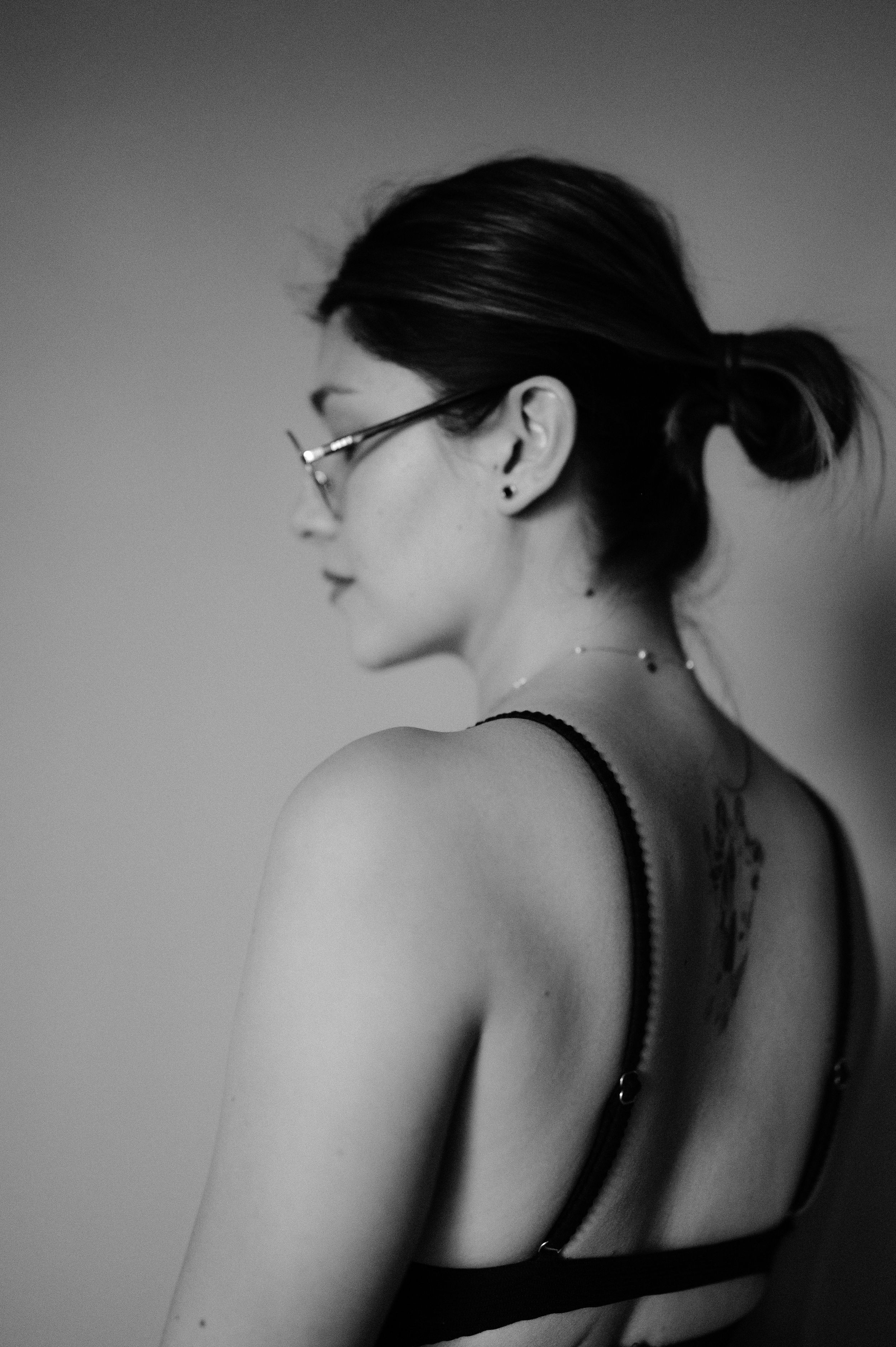 Black and white profile portrait showing back tattoo and elegant updo.