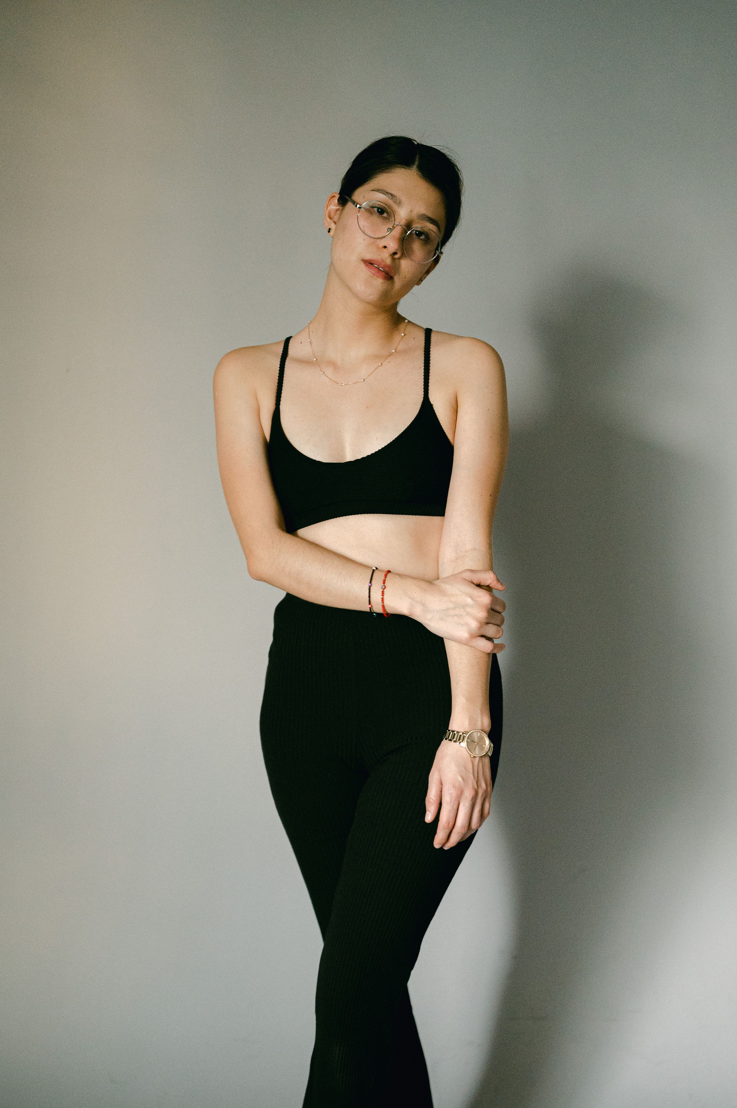 Figure in black athletic wear strikes a confident pose against a neutral wall.