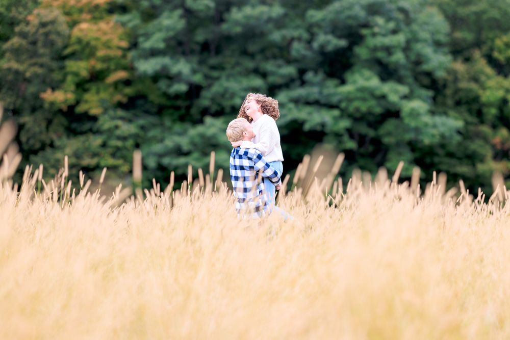 Couple Having Fun in Tall Grass During Engagement Photo Session at Ransom Sage Farm in Chardon, Ohio