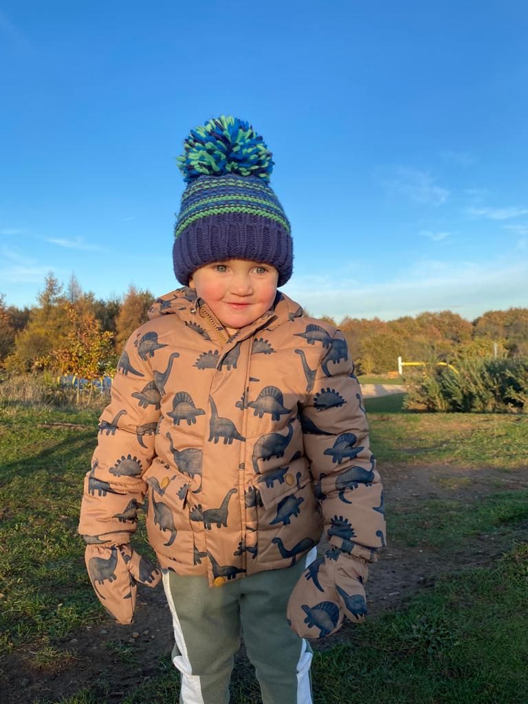 little boy wearing a wooly hat and brown dinosaur coat on a sunny day, taken by photographer in DN7.