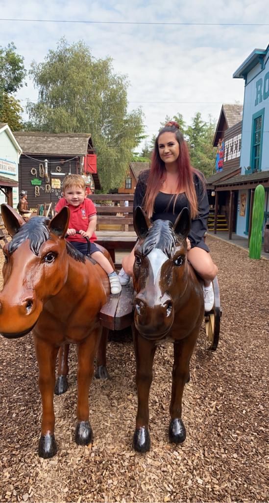 Mother and son sat on pretend horses smiling for a photo by photographer in DN7.