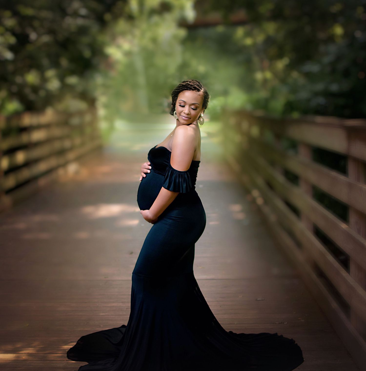 Elegant maternity photograph on a wooden bridge featuring a navy blue flowing dress.