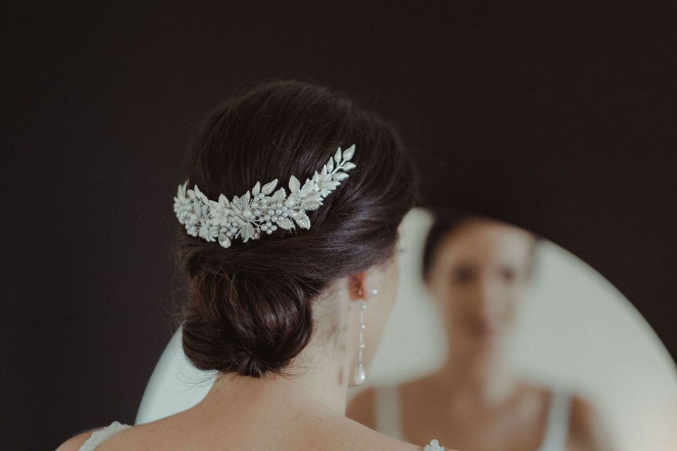 Detalhe elegante de acessório de cabelo para noiva com delicado design de folha prateada.