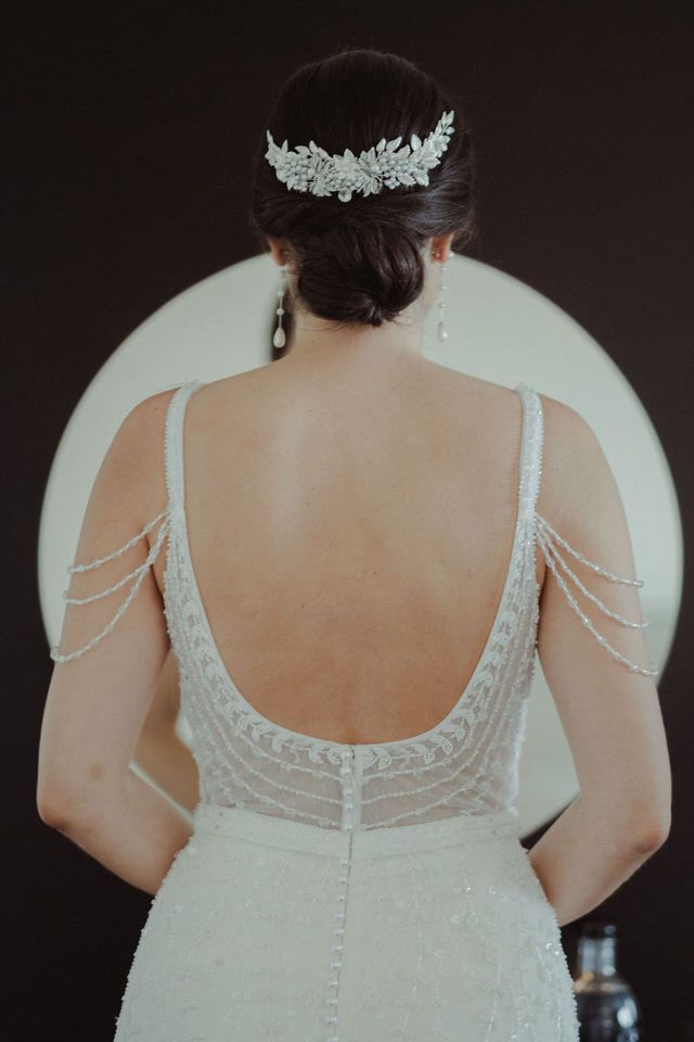 Pormenor das costas de um vestido de noiva mostrando bordados complexos e fecho com botões.