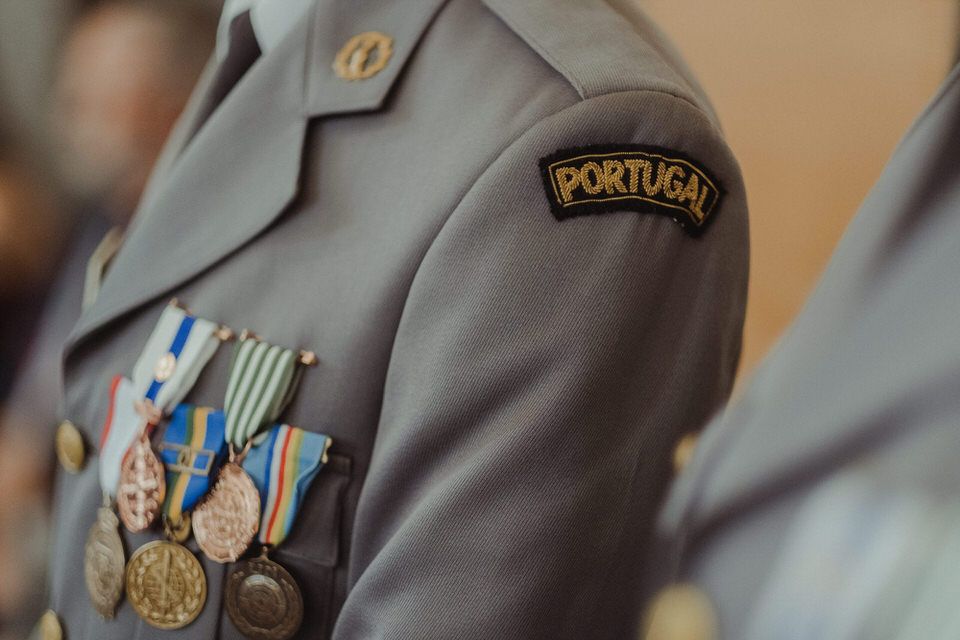 Pormenor da manga de um uniforme militar português, mostrando medalhas e distintivos.