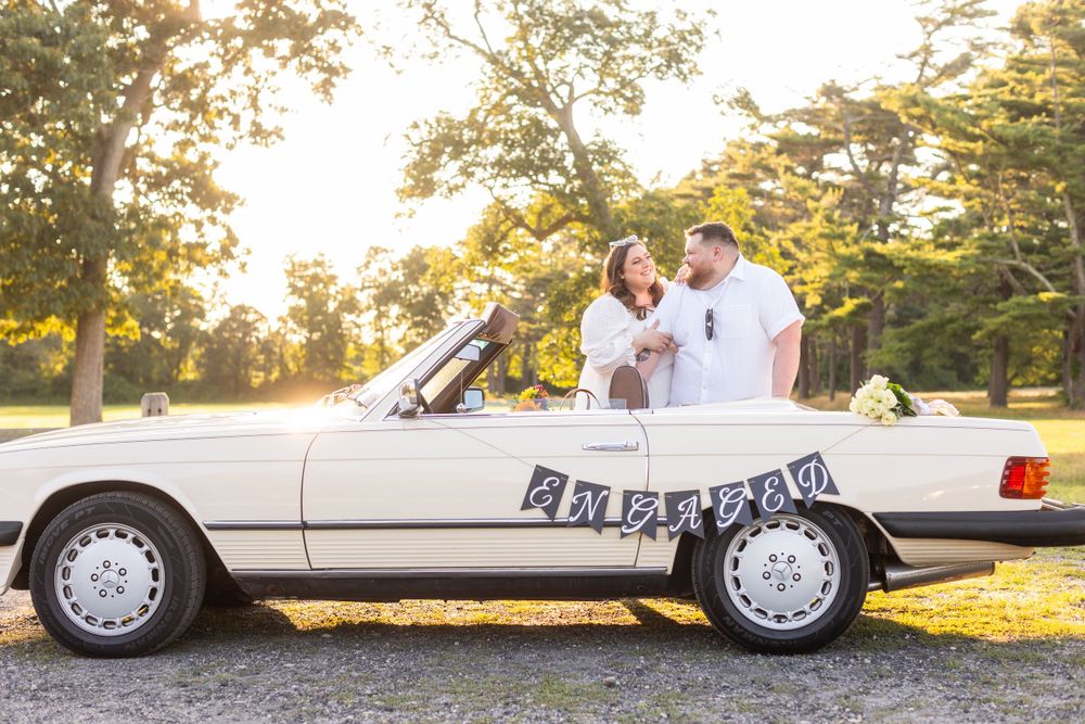 White vintage Mercedes convertible decorated with Just Married banner in golden sunset light.