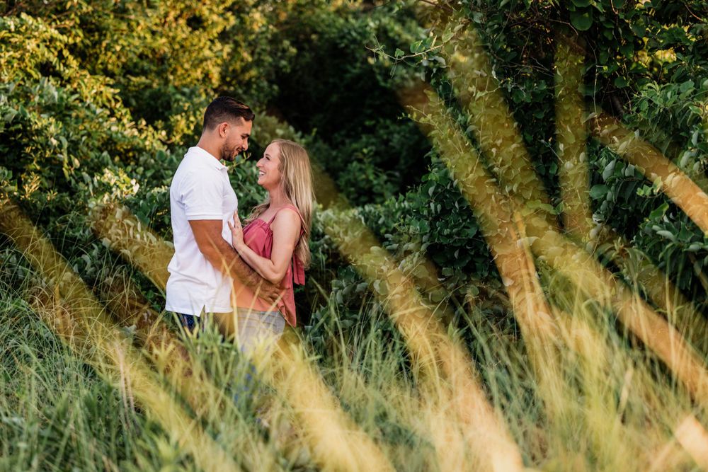 Summer meadow portrait with tall grass framing the intimate moment.