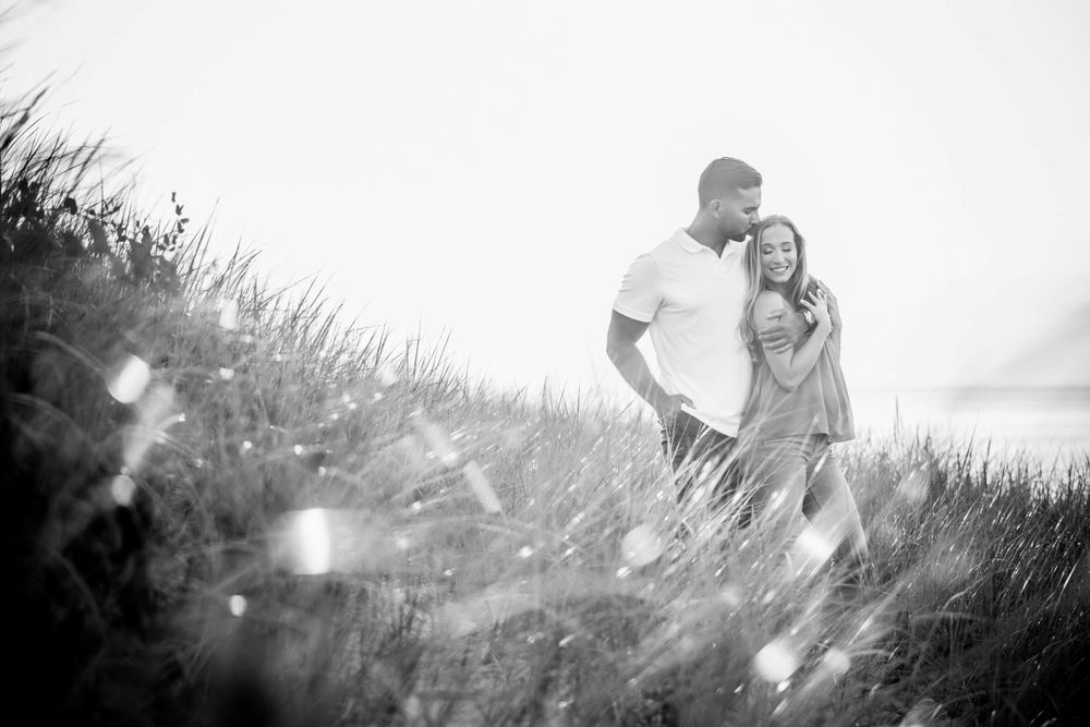 A dreamy black and white photo of a couple standing together in misty outdoor lighting.