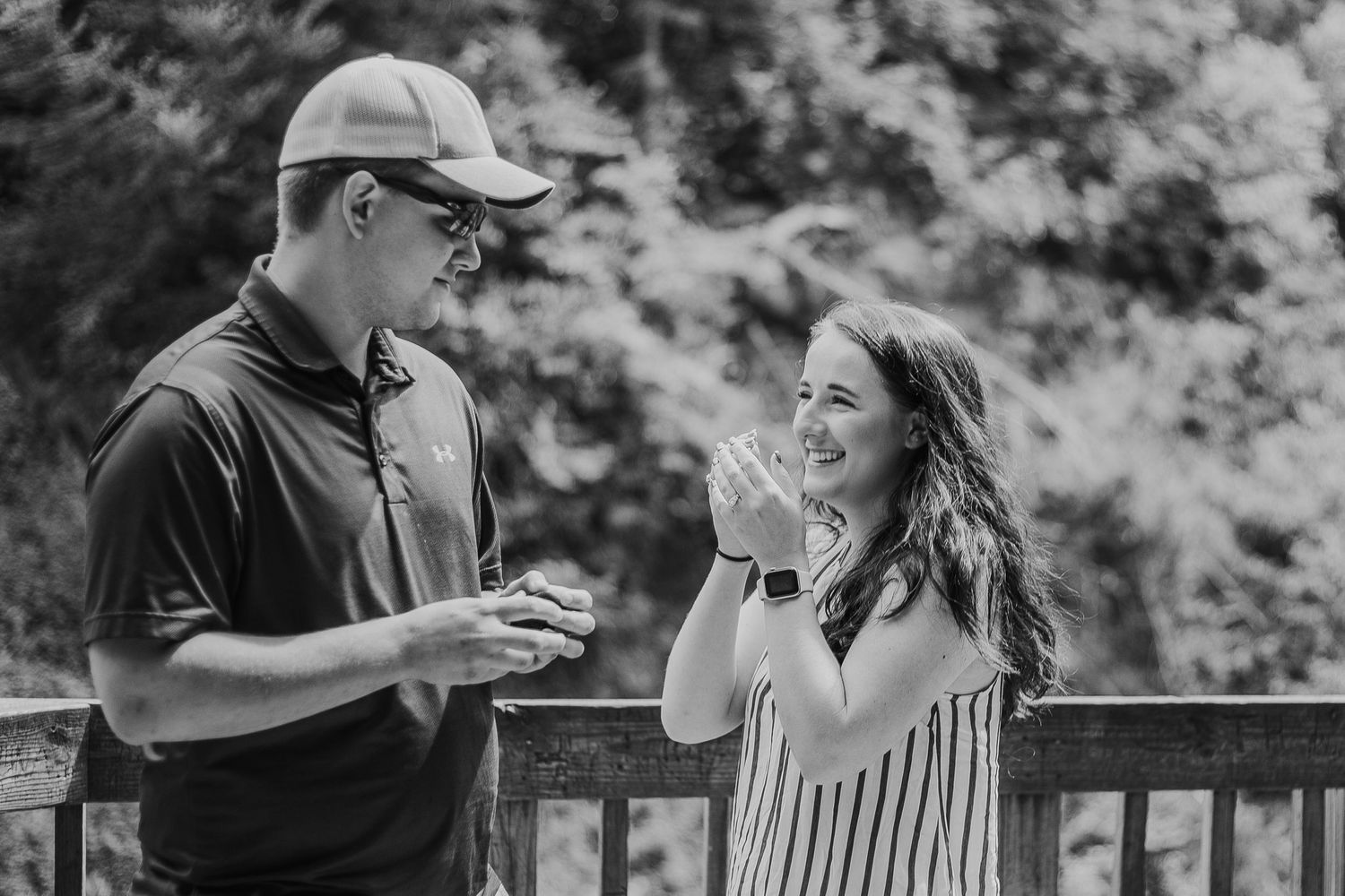 A black and white capture of a surprise proposal moment on a scenic mountain overlook.