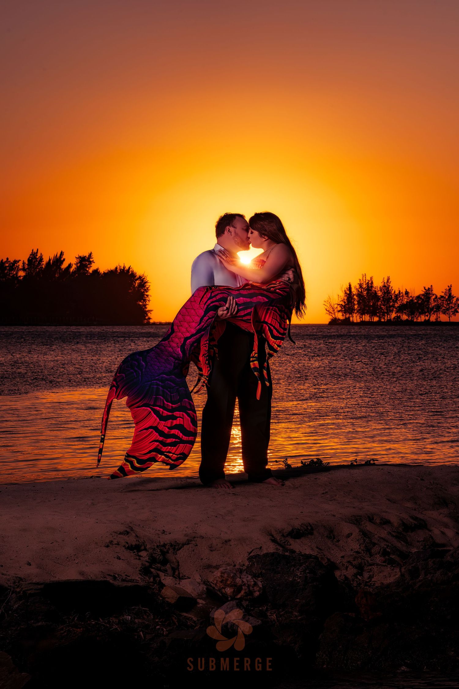 Romantic silhouette of couple embracing on beach during golden sunset.
