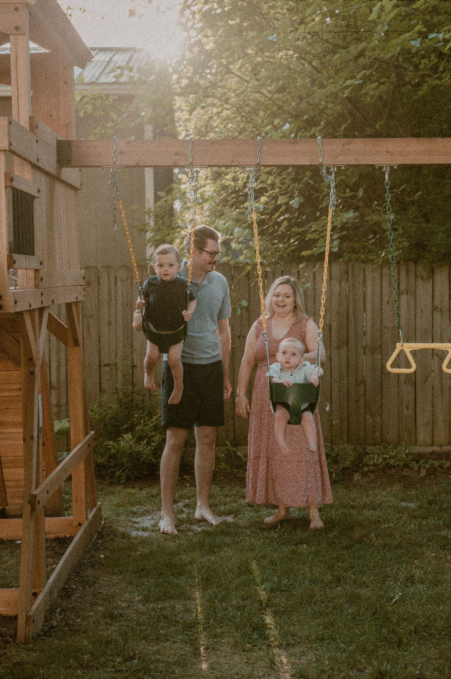 A family enjoys a warm evening together at their backyard wooden playset during golden hour sunset. photo by Samantha Campbell imagery