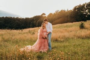 Romantic sunset maternity photo in field with flowing pink dress.