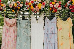 Vintage floral dresses in pastel colors hanging on a clothesline under a flower arch.