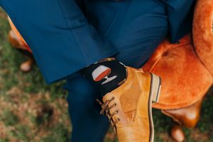 Close-up view of tan leather boots with brown laces against a dark blue background and rustic outdoor setting.