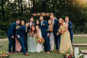 Wedding party in navy and pastel attire gather for group photo at outdoor garden reception in East Texas.