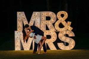 Illuminated marquee letters spelling 'MR & MRS' set up at night against a dark background.