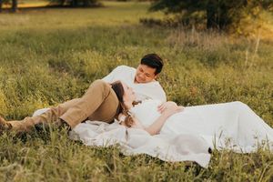 A person in a white dress rests peacefully on a blanket in a sunlit meadow during golden hour.