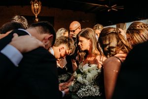 A series of candid wedding reception photos showing emotional moments and dancing between guests in dim lighting.