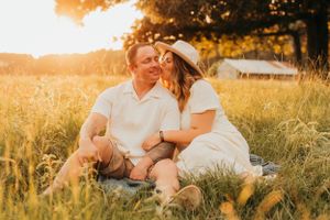 Couple sharing intimate moment while sitting in golden wheat field at sunset.