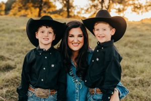 A Western-themed family portrait in matching denim and black cowboy hats against a golden sunset meadow background.