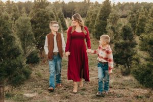Family walks together through pine forest during golden hour photo session.