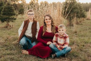 Family sitting together in a golden field at sunset wearing coordinated fall outfits.