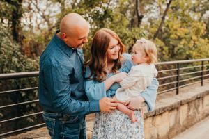 Family sharing intimate moment together on stone bridge in autumn setting.