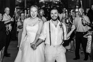 Black and white photo of newlyweds celebrating during wedding reception exit.