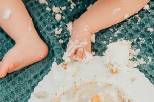 Close-up shot of bare feet on a teal blanket with cake crumbs scattered about.