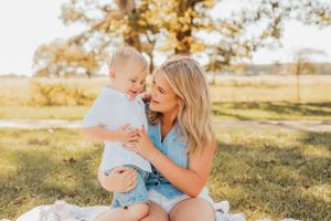 Parent and toddler sharing joyful moment on blanket under golden tree.