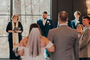 A wedding party stands together during a reception celebration in an elegant indoor venue.