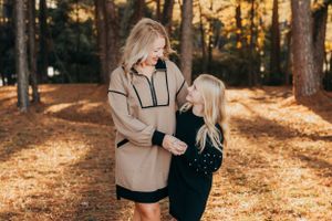 Mother and daughter sharing a tender moment among fall foliage.