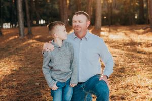 Father and son share a warm moment in an autumn forest setting.