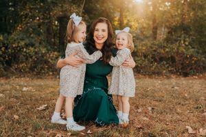 A mother and daughters share a joyful moment together outdoors during golden hour.