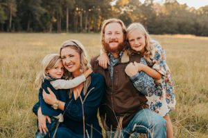 A family shares an intimate moment together in a sunlit meadow.