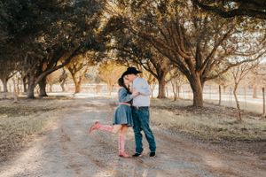 Romantic couple embracing on a tree-lined dirt path during golden hour.