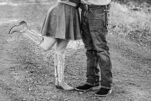 Black and white photo showing cowboy boots and jeans in a romantic country setting.