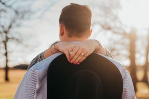 Close-up shot of an embrace showing hands on shoulders in soft evening light.