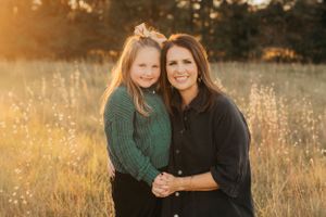 Two people in warm sweaters pose together in a golden autumn field.